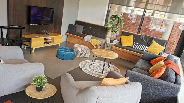 A modern living room with a sofa, armchairs, a coffee table, and a TV. - Student Only The Towpath (Chester)