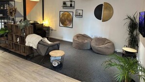 A modern living room with a sofa, two bean bags, a coffee table, and a TV mounted on the wall. - Student Only The Towpath (Chester)