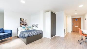 A modern bedroom with a bed, a blue sofa, and a desk with a chair.