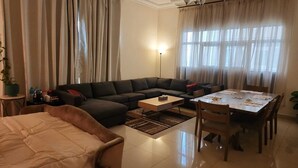Ein Wohnzimmer mit einer Couch, einem Couchtisch, einem Esstisch mit Stühlen und einer Lampe.