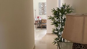 Ein Flur mit Essbereich im Hintergrund, einem Tisch mit Lampe und einer Zimmerpflanze.