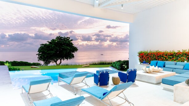 Un'area lounge esterna moderna con piscina, poltroncine blu e divanetti.