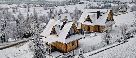 Eine verschneite Landschaft mit einer Holzhütte, einem geneigten Dach und einer kleinen Veranda.