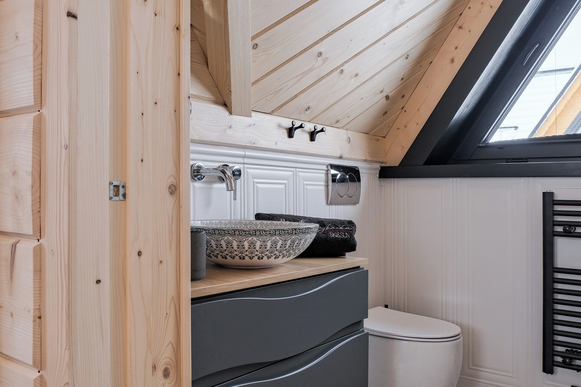 A compact kitchen with a white sink, black faucet, and patterned bowl on the counter.