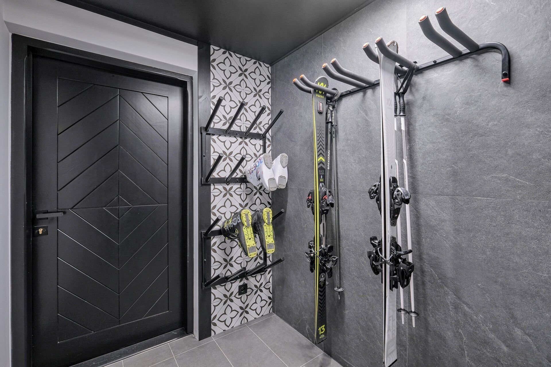 A modern ski storage area with wall-mounted racks and a door with a geometric pattern.