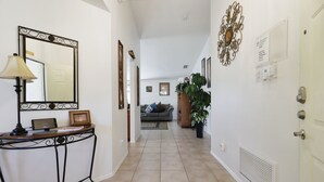 A hallway with a mirror, a table with a lamp, a sofa, and a potted plant. - Stress-Free Disney Stay-Private Pool & Fenced Yard (Kissimmee)