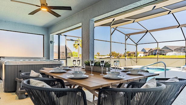 Un espace extérieur aménagé pour les repas, avec un jacuzzi, des fauteuils en osier et une vue sur le paysage environnant.