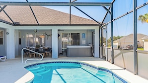 Une piscine extérieure couverte avec un jacuzzi, une terrasse dotée de chaises et une vue sur le quartier.