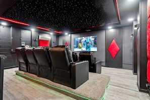 A home theater with a starry ceiling, a large screen, and leather recliners.