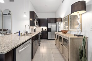 Una cocina moderna con armarios oscuros, electrodomésticos de acero inoxidable y encimera de granito.