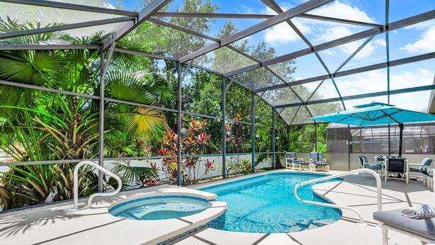 Un espace piscine comprenant un jacuzzi, des chaises longues et un coin salon couvert avec des parasols.