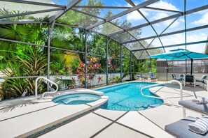 Een zwembad met een jacuzzi, ligbedden en een overdekt zitgedeelte met parasols.