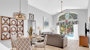 Un salon moderne avec un coin repas, un canapé gris et un ventilateur de plafond.