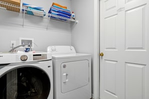A laundry area with a washing machine, dryer, and a shelf with folded towels. - Perfect Family Disney Escape: Pool & Games (Kissimmee)