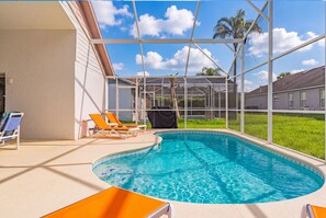A swimming pool with a glass enclosure, surrounded by lounge chairs and a grassy area. - Perfect Family Disney Escape: Pool & Games (Kissimmee)