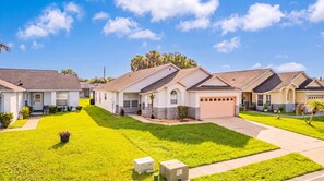 A row of single-family homes with front yards, a clear sky, and a well-maintained lawn. - Perfect Family Disney Escape: Pool & Games (Kissimmee)