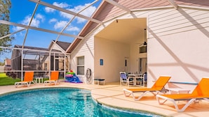 Ein Pool im Freien mit Liegestühlen und einer überdachten Terrasse.
