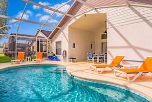 An outdoor swimming pool with lounge chairs and a covered patio area. - Perfect Family Disney Escape: Pool & Games (Kissimmee)