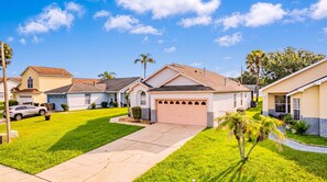A residential neighborhood with single-family homes, a driveway, and a well-maintained lawn. - Perfect Family Disney Escape: Pool & Games (Kissimmee)