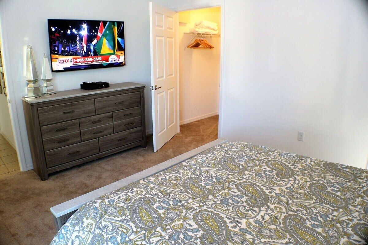 A bedroom with a bed, a dresser, a TV, and a closet.
