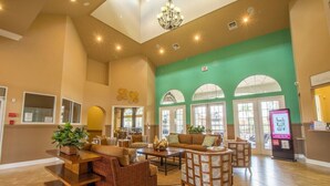 A spacious lobby with a high ceiling, a reception desk, and comfortable seating areas. - Magical Disney Villa • Sunny Pool, Spa & Game Room (Kissimmee)