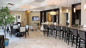 A modern kitchen with a bar area, featuring a large island, dark chairs, and pendant lighting. - Luxury Resort Villa with Pool, Spa – Perfect for Families! (Davenport)