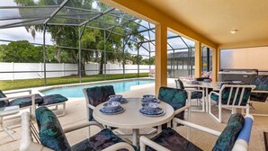 Une terrasse extérieure dotée d’une véranda en verre, d’une piscine et de sièges agrémentés d’assiettes bleues et blanches.
