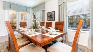 A dining room with a wooden table set for six, surrounded by cushioned chairs. - 6BR Disney Area Villa, South Facing Pool, Spa, Game Room (Davenport)