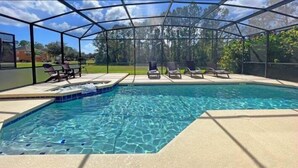 A swimming pool with a glass enclosure, surrounded by lounge chairs and a hot tub. - 6BR Disney Area Villa, South Facing Pool, Spa, Game Room (Davenport)