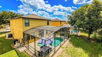 Una casa con un patio techado, piscina y césped.