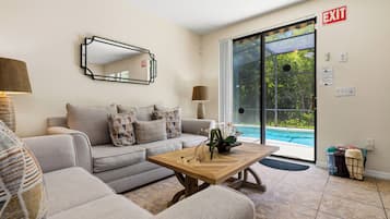 Una sala de estar con sofá, mesa de centro y vista a la piscina.