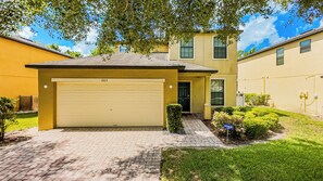 A residential building with a garage, a well-maintained lawn, and a clear sky. - Near Disney, Game Room, BBQ & Free Pool Heat + Late Checkout (Davenport)