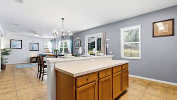 A kitchen with a central island, wooden cabinets, and a dining area with chairs and a table.