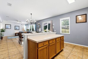 A kitchen with a central island, wooden cabinets, and a dining area with chairs and a table.
