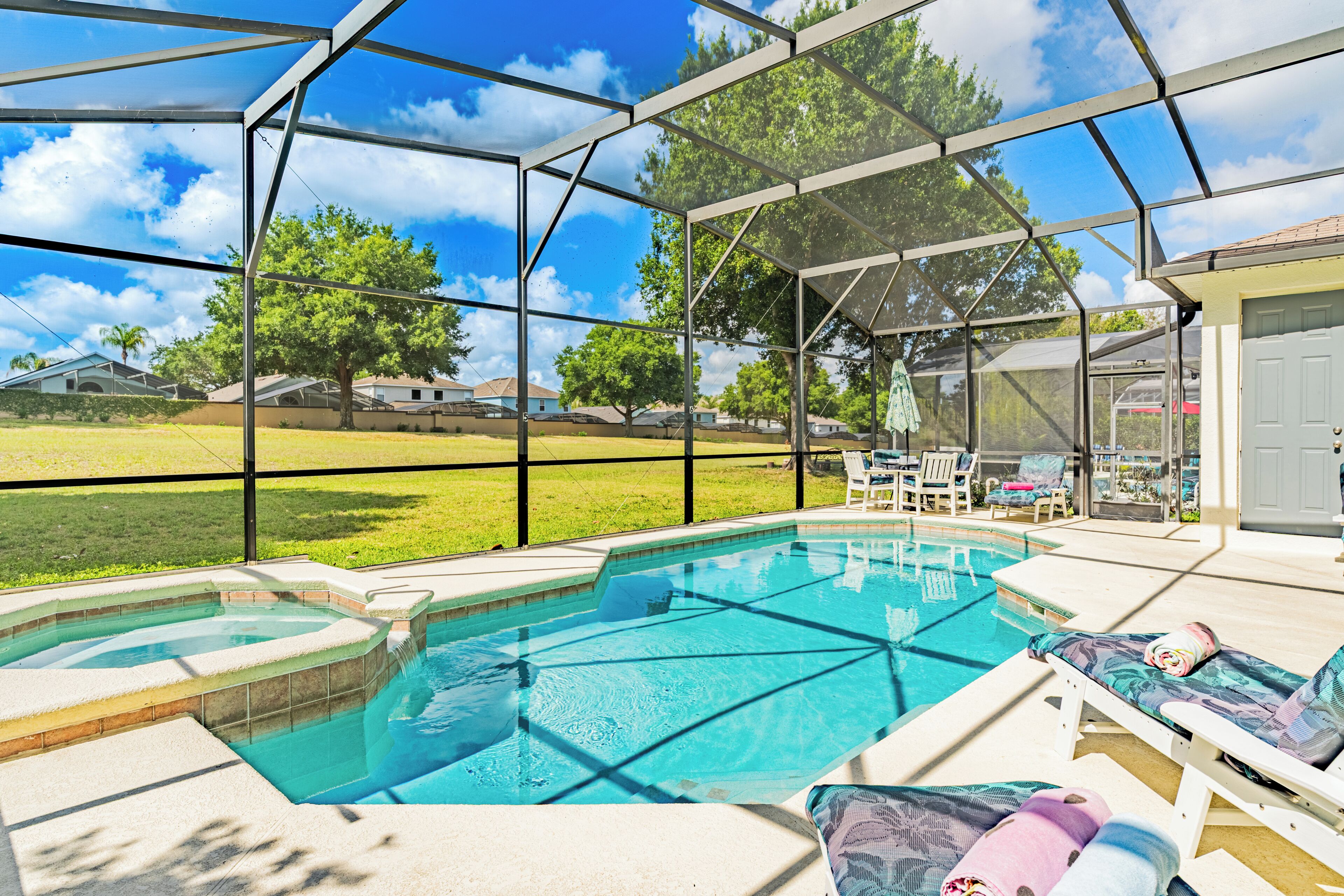 A covered outdoor swimming pool with lounge chairs and a view of the surrounding neighborhood.