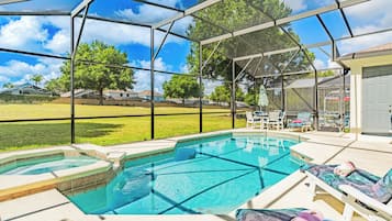 A covered outdoor swimming pool with lounge chairs and a view of the surrounding neighborhood.