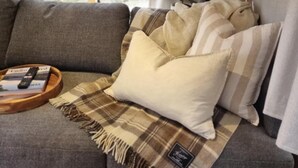 A cozy living area with a sofa, pillows, a blanket, and a tray with a remote control. - Escape to a unique retreat with Miss Beddy, recently renovated Bedford bus  (Mount Helen)