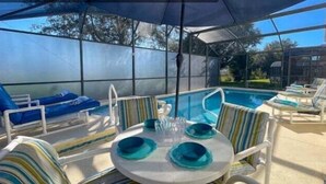 Un área de piscina al aire libre con sillones de descanso y una mesa dispuesta para comer.