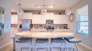 A modern kitchen with a central island, stainless steel appliances, and pendant lighting. - 6-Bedroom Home with Private Pool, Spa & Game Room (Davenport)