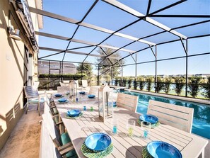 An outdoor dining area with tables and chairs, a pool, and a view of the surrounding landscape. - 6BR Solterra Villa with Pool, Spa & Lake View (Davenport)