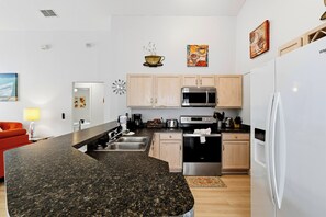 A modern kitchen with granite countertops, stainless steel appliances, and wooden cabinets.