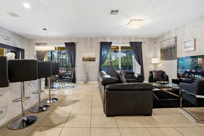 Una sala de estar moderna con un sofá, una mesa de centro, un televisor y una zona de bar con taburetes.