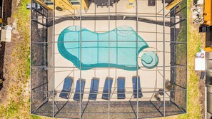 On peut apercevoir une piscine au design original, entourée d’une clôture métallique, ainsi que plusieurs chaises longues.