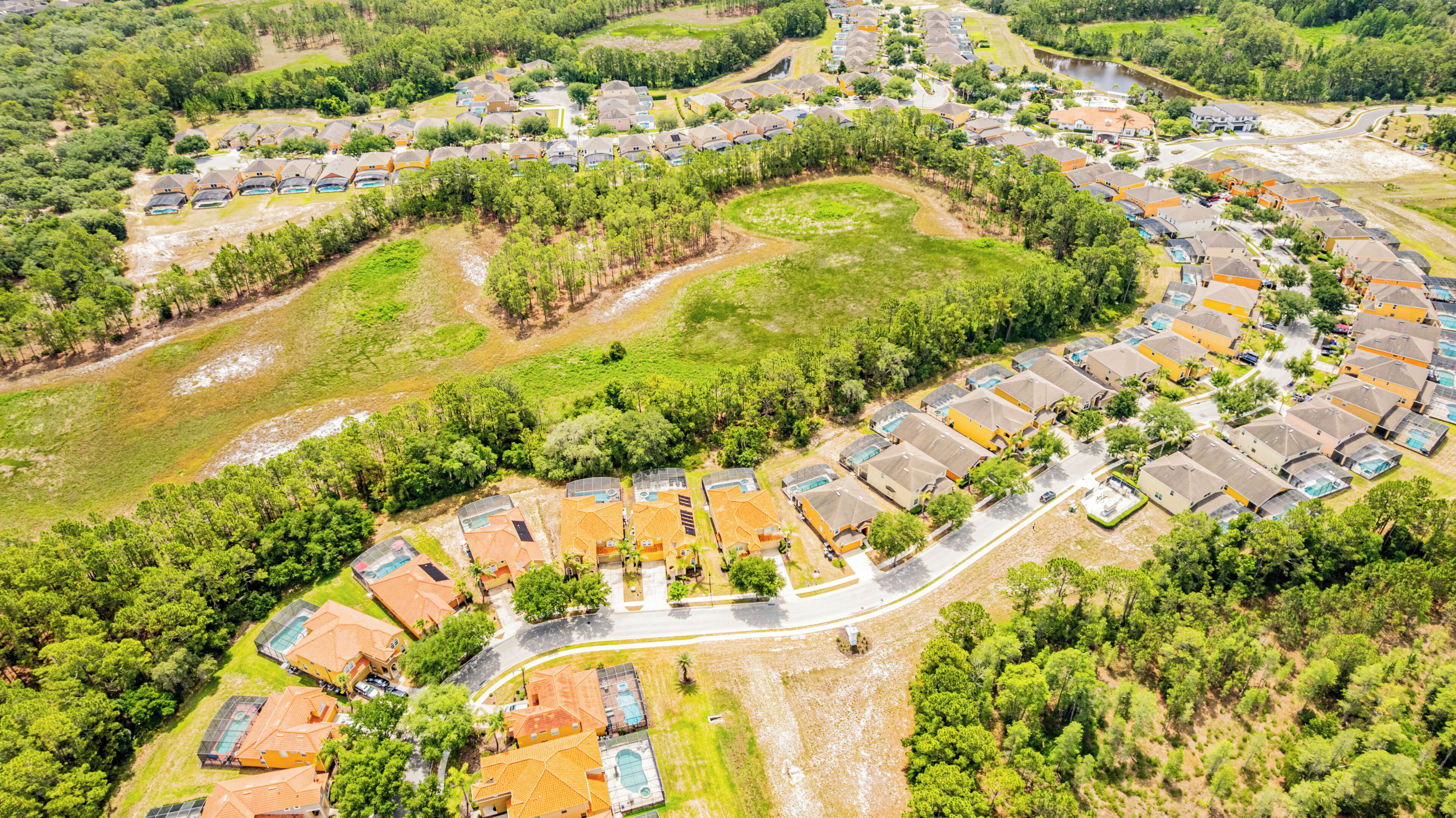 Oversigtsbillede af et boligområde med huse i en buet anordning, omgivet af grønt og en flod.