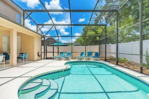 Piscina com área coberta, espreguiçadeiras e vista para um edifício ao fundo.