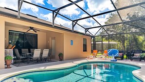 Piscina con cerramiento de vidrio, zona de estar al aire libre y terraza cubierta.