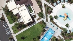 An aerial view of a hotel with a swimming pool, a circular water feature, and a parking lot. - Dream Disney Themed Villa • Pool, Movie & Games! (Kissimmee)