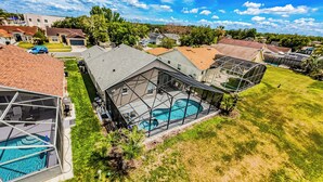 Eine Wohngegend mit einem großen Haus, das einen Pool, eine überdachte Terrasse und eine Garage hat.