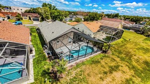 Eine Wohngegend mit einem großen Haus, das einen Pool, eine überdachte Terrasse und eine Garage hat.