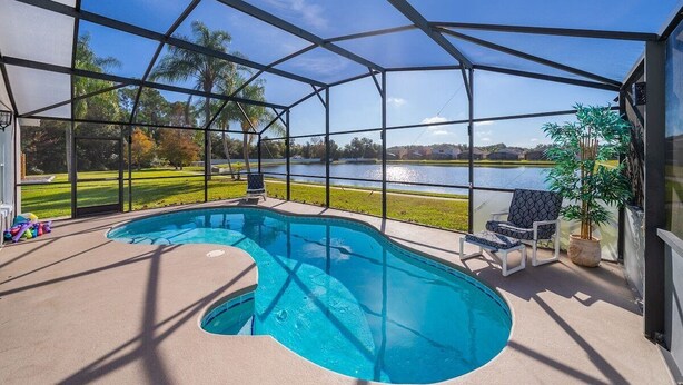 A covered outdoor swimming pool with a view of a lake and a grassy area.